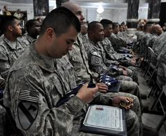 Army Pfc. Aldo Flores receives flag during naturalization ceremony in Baghdad