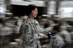 Army Pfc. Jea Lee walking back to her seat after being naturalized as a U.S. citizen at Al Faw Palace on July 4