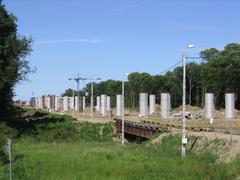 Construction of a highway overpass of the Wrocław Motorway Bypass leading to the Rędziński Bridge, temporary steel bridge over the Ślęza River in the foreground, view from southwest to northeast