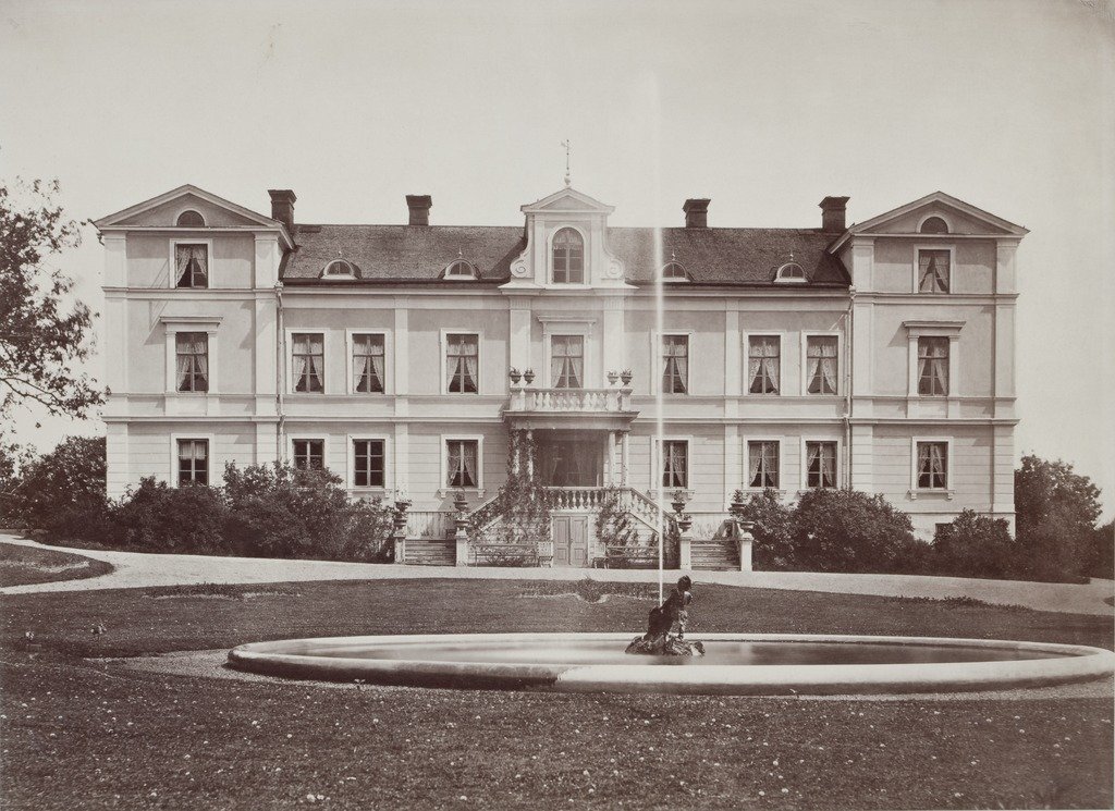 Photograph of Erikslund Manor in Sweden surrounded by green trees and clear blue sky