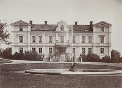 Photograph of Erikslund Manor in Sweden surrounded by green trees and clear blue sky