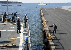 Finnish line handler throws lines to sailors aboard USS Laboon guided-missile destroyer as it departs Helsinki port