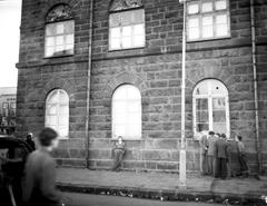 East side of Althingi building with broken windows and youths standing outside after 1949 NATO riot in Iceland