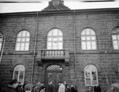Front view of Althingi with people passing by and broken windows after 1949 riot