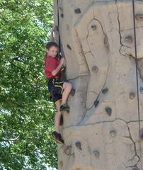 Boy climbing rock tower outdoors under rock arch in St. Louis