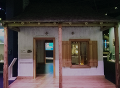 White Creole log cabin with open door and window at the Gateway Arch museum exhibit