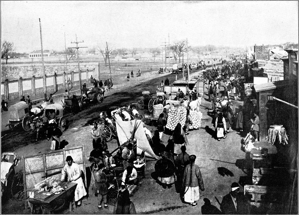 Vintage street scene in Peking with traditional buildings and horse-drawn carts in 1906