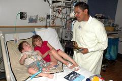Seaman Alex Franco presenting a USS Winston S. Churchill Navy ball cap to a patient and his sister at Children’s Hospital of Philadelphia during Navy Week