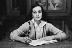 Wax figure of Anne Frank seated at a table in the Anne Frank House exhibit at Madame Tussauds wax museum in Amsterdam