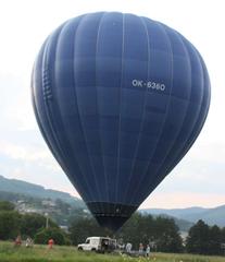 Colorful balloons flying above a dry, empty dam under a clear blue sky