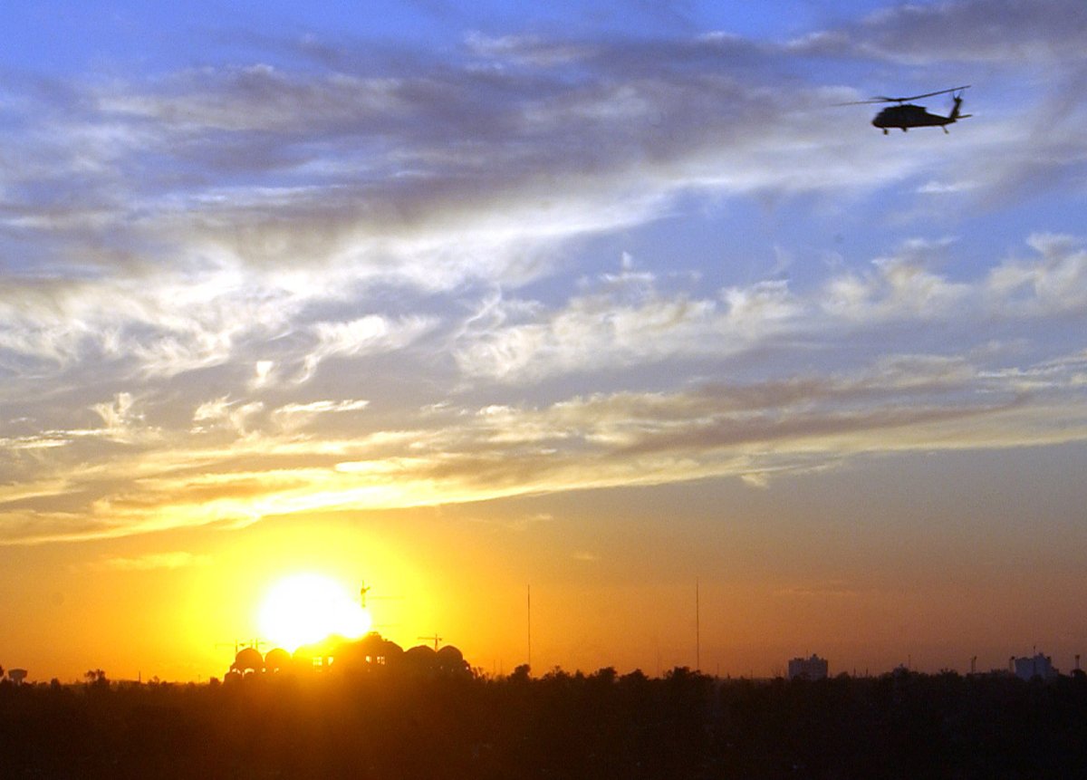 UH-60 Black Hawk helicopter flying at sunset over Baghdad with Al Rahman mosque under construction