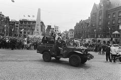 Historical black and white photo of Canadians liberating Amsterdam on May 5, 1980, crowd gathered on the Dam square
