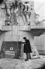 American painter George Yalick painting at the National Monument on Dam Square in Amsterdam on February 23, 1970