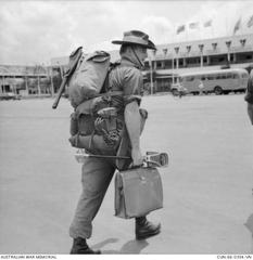Australian soldier Captain John Raftery arriving at Tan Son Nhut Airport with packs, briefcase, and shooting stick