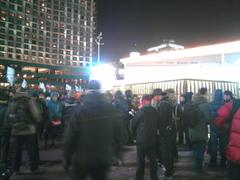 Ice rink with people skating cheerfully next to a general strike demonstration at Seoul City Hall Plaza