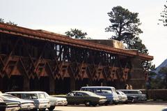Cars parked outside Mission 66 building surrounded by trees and mountains in Rocky Mountain National Park