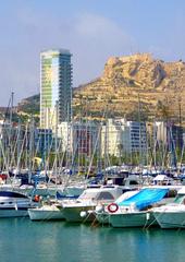 Marina of Alicante with boats moored at docks under a cloudy sky