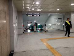 Interior view of Sinseol-dong Station transfer passage connecting Seoul Subway Line 1, Line 2, and Ui LRT with directional signs and tiled walls