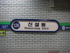 Interior view of Sinseol-dong Station platform with passengers and train tracks