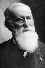 John Ogden studio portrait with beard, suit, and glasses