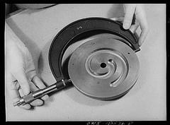 Students in New York University precision instrument training class inspecting a cast iron cam with a micrometer caliper