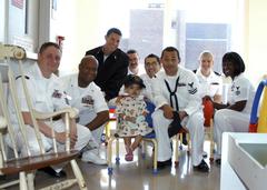 Sailors from USS Bataan sharing time with a young girl at Boston Medical Center during Boston Harborfest community project