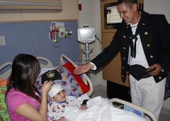 US Navy Damage Controlman Fireman Javier Ibarria giving a Navy ball cap to a patient at Boston Medical Center during Caps for Kids event