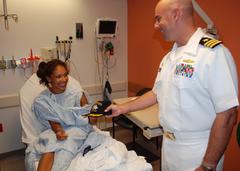 Commander Timothy M Cooper of USS Constitution giving Navy ball cap to patient at Boston Medical Center during Caps for Kids event