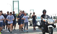 Service members and volunteers running a torch relay across the Vincent Thomas Bridge at night honoring POW/MIA