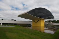 View of Oscar Niemeyer Museum in Curitiba, Paraná, Brazil, showcasing modern architectural elements and surrounded by lush greenery under a blue sky