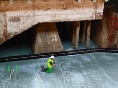 Construction worker working underground during Central Station Amsterdam renovation, old brick foundation with new concrete support