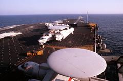 Elevated view of the flight deck aboard USS John F. Kennedy aircraft carrier with an E-2C Hawkeye airborne early warning aircraft and an F-14A Tomcat fighter jet