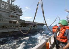 Phone talker watches USS John F. Kennedy aircraft carrier refueling at sea during underway replenishment