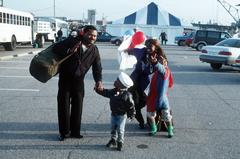 Crewman and family moving away from the pier where aircraft carrier USS John F. Kennedy (CV-67) is moored at Naval Air Station Norfolk