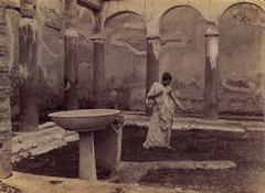 Youth wearing a toga in the patio of Casa degli Archi, Pompeii, photographed by Wilhelm von Gloeden
