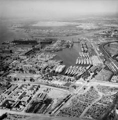 Aerial view of the Philadelphia Naval Shipyard Reserve Basin with numerous U.S. Navy cruisers, escort carriers, and auxiliaries in reserve on 19 May 1955