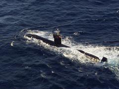 USS Dolphin diesel-powered auxiliary research submarine pulled by tugboat toward shore after fire and flooding in Pacific Ocean