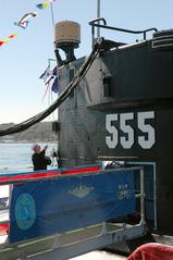 Sailor hoisting Commanding Officer's pennant aboard USS Dolphin submarine during change of command ceremony