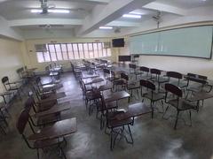 Fisheye view of a classroom in Julian Felipe Hall at De La Salle University – Dasmariñas with desks and chairs arranged neatly, colorful walls, and ceiling lights