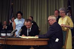 President Lyndon B. Johnson signing Medicare Bill at Harry S. Truman Library with Harry S. Truman and dignitaries