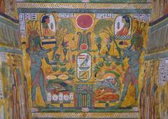 Painted panel from the inner lid of Sennedjem's coffin showing two green-skinned deities offering food and plants with a central solar disk and offerings scene