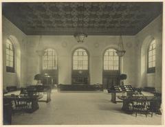Main reading room of the Detroit Public Library with rows of wooden tables and chairs under ornate ceiling