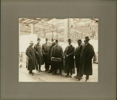 Nine overcoated and hatted men laying cornerstone of Detroit Public Library in 1917