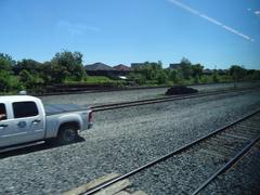 View through train window showing urban landscape with trees and railway tracks heading towards Pearson Airport