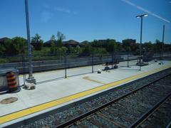 View from train window showing railway tracks and greenery during daytime