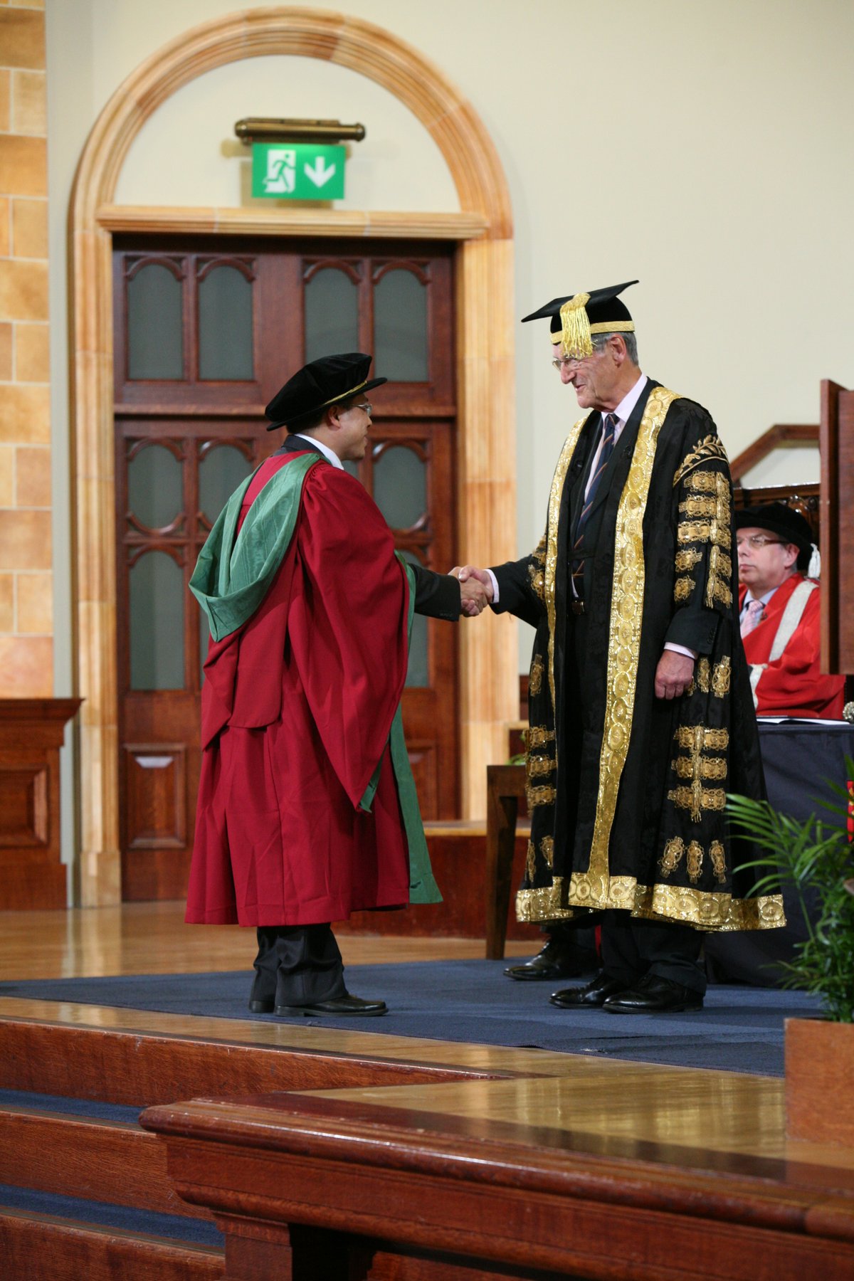 PhD graduand shaking hands with Sir Dominic Cadbury at University of Birmingham Great Hall