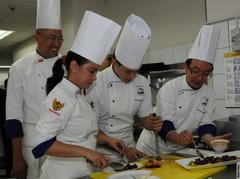 American and Indonesian chefs demonstrating cooking techniques during a cultural culinary event