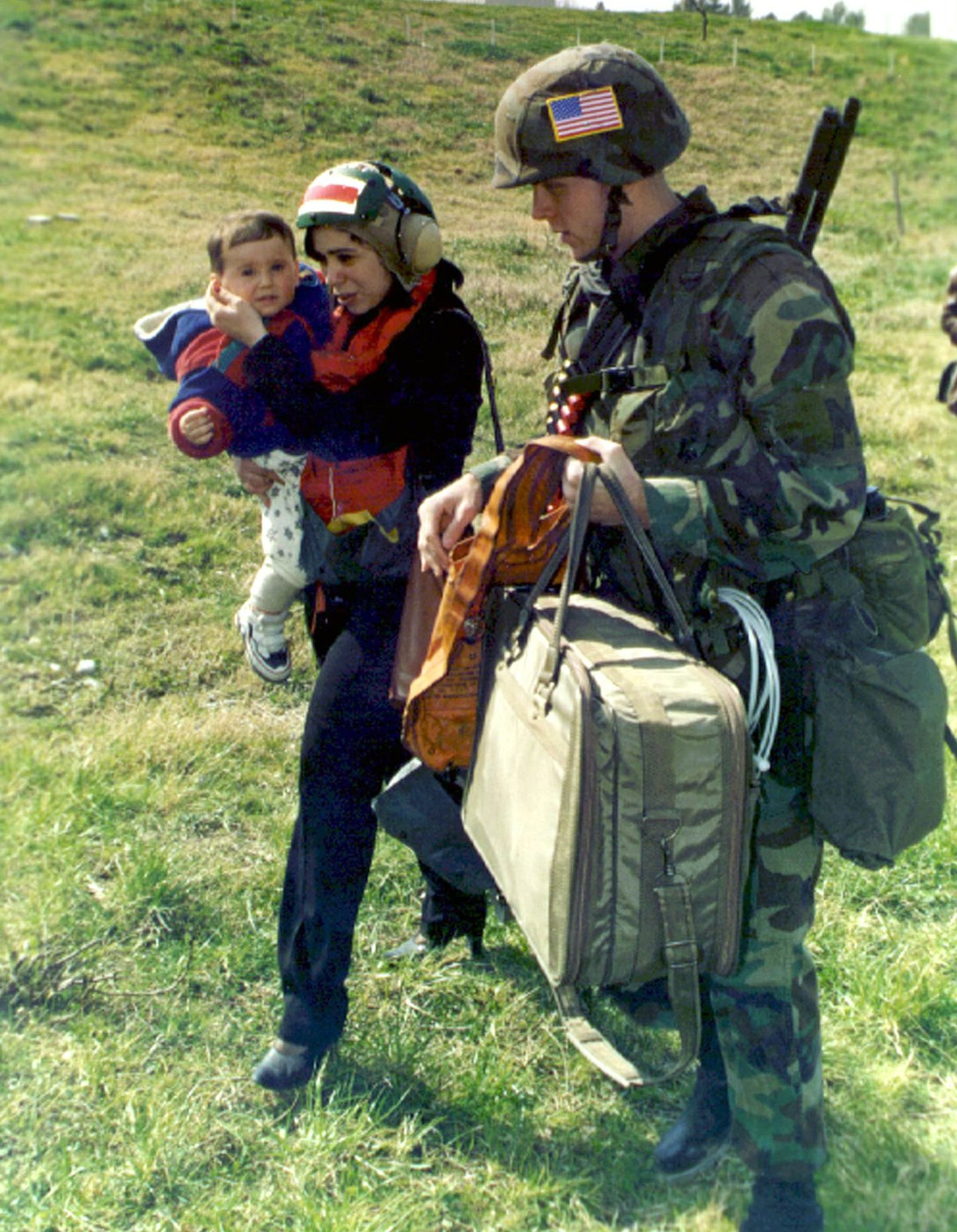 U.S. Marine Corps Military Policeman escorting woman and child to helicopter during Operation Silver Wake in Albania