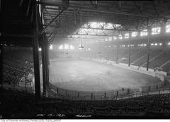 Interior view of Exhibition Coliseum in 1921 with open wooden roof trusses and a large, mostly empty space