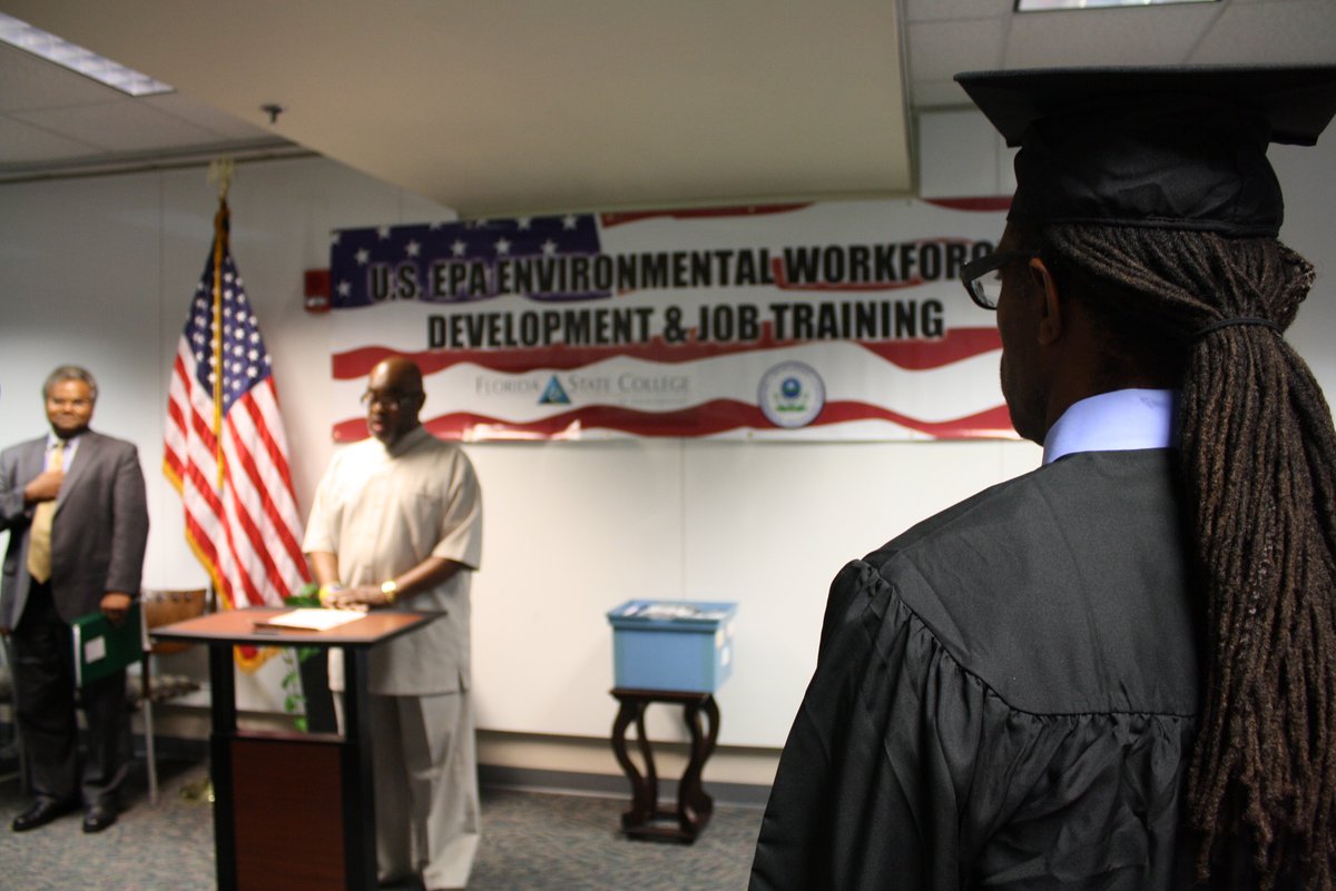 Graduate watching FSCJ brownfields program graduate sing national anthem at Environmental Workforce Development and Job Training graduation